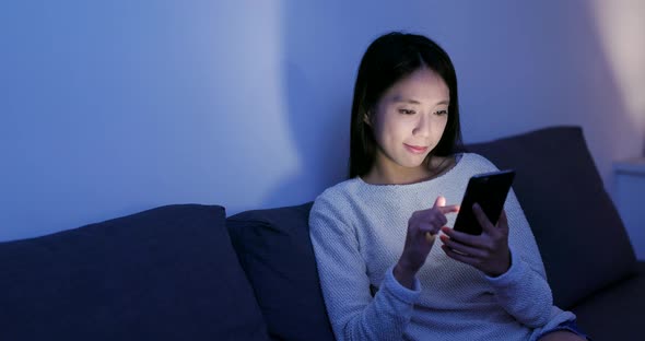 Woman use of mobile phone at home in the evening alt