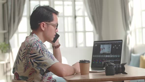 Asian Man Editor Talking On Mobile Phone With Video Editing App / Software On His Laptop Computer alt