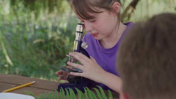 Girl at outdoor school looking through microscope