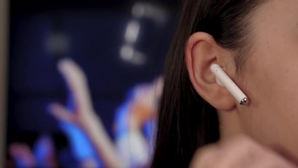Young Woman Using Wireless Earbuds and Listening to Music