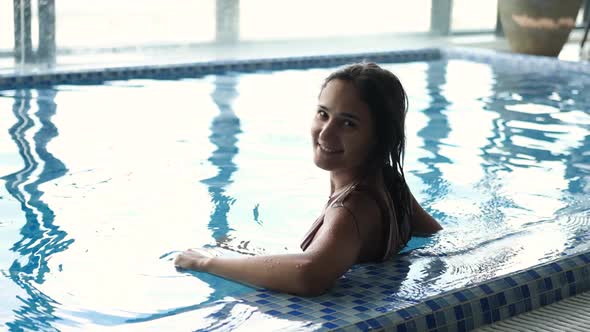 Closeup Shot of Young Woman Enjoying and Relaxing in Indoor Swimming Pool Looking at Camera and alt