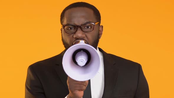 Angry African-American Boss in Suit Using Megaphone to Yelling on Employees alt