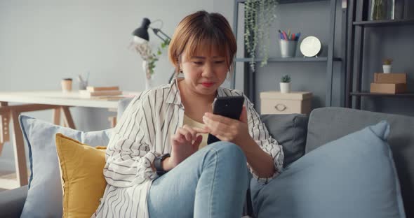 Asia lady using smartphone text message or check social media on sofa in living room at house.