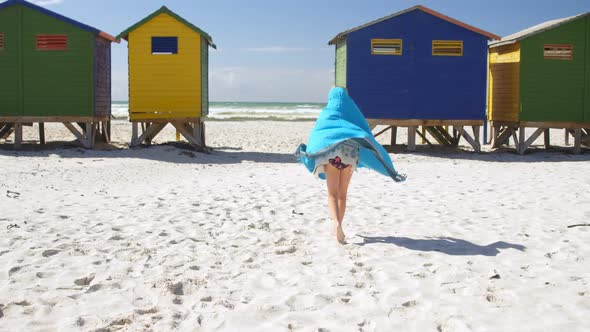 Girl with towel walking in the beach alt