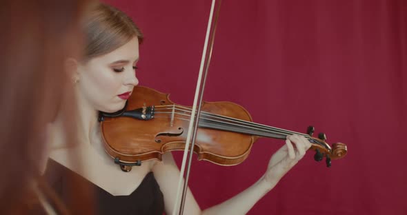 Close View of Female Musicians Duet Playing the Violins at Camera Indoor alt