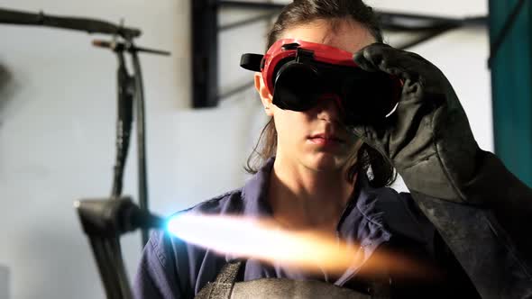 Female welder welding a metal alt