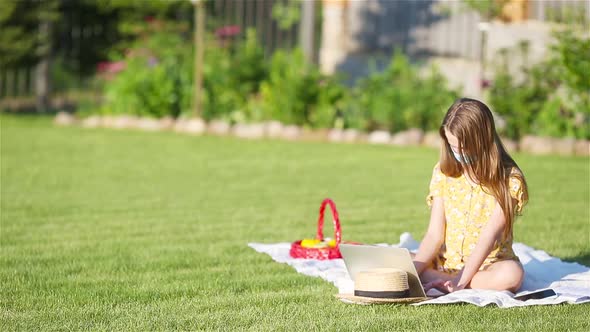 Little Girl Outdoors in the Park with Computer