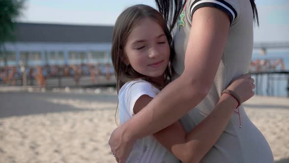 Portrait of Happy Mother and Daughter 9 Years Standing Hugging Against the Backdrop Near Beach in alt