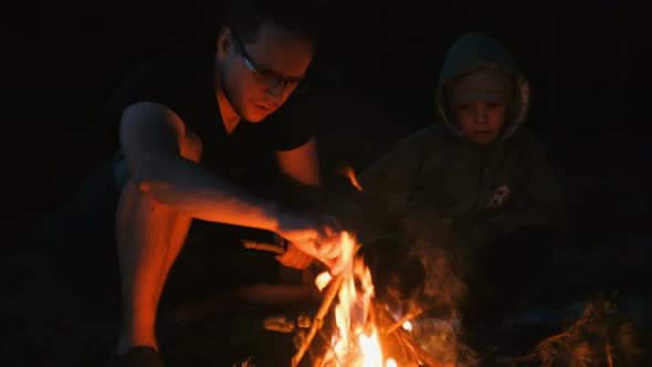 Son and Dad Light a Fire in the Forest. Family Camping