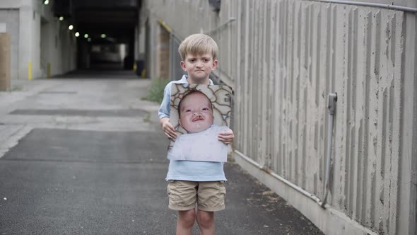 Slow motion of young boy holding up baby photo of himself with cleft palate. alt