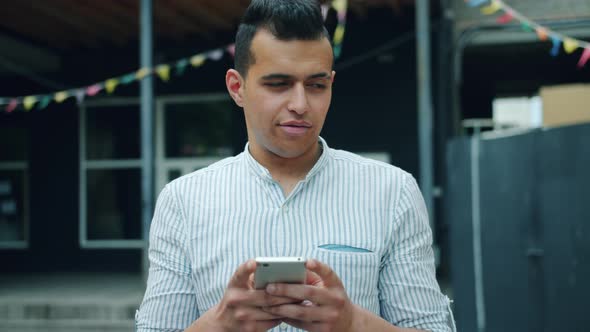 Portrait of Handsome Mixed Race Man Using Smartphone Touching Screen Outside alt