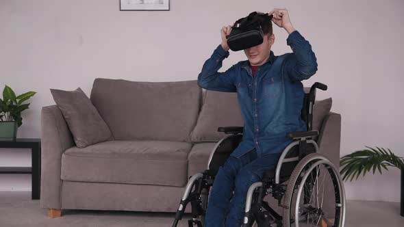 Disabled Man Teenager in Wheelchair Putting on VR Goggles and Playing Games in Virtual Reality