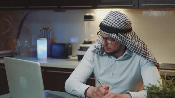 Arab Man with Kandora Receiving Telephone Call While Working at Home Office