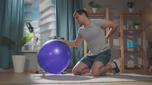 Severe Pain in a Man During a Fitness Class on a Gym Ball at Home alt