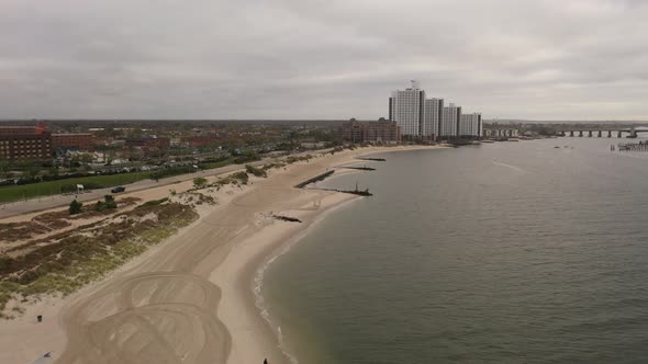 An aerial shot over the East Rockaway Inlet in NY. The drone dolly in to tall white buildings & the alt