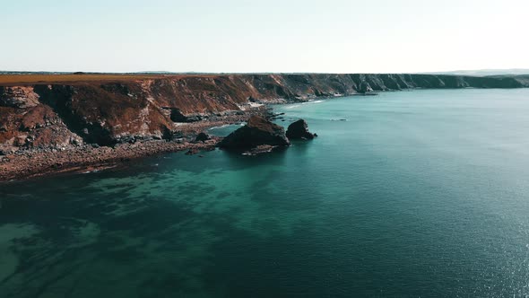 Rocks off the ocean coast line with turquoise water and dramatic cliffs Aerial view.