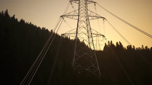 High voltage electricity pylons in a mountain forest during sunset. 4k alt