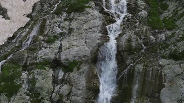 Aerial View of a Glacial Waterfall High in the Mountains on a Sunny Day alt