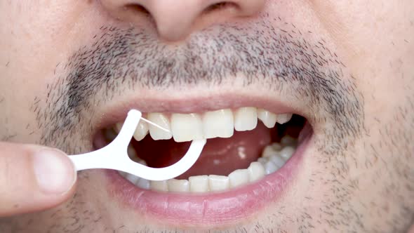 close up4 k video man's mouth smiling and flossing his teeth with a white plastic toothpick. lips.na alt