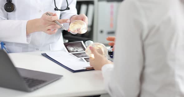 Doctor Surgeon Shows Silicone Breast Implant to Patient in Clinic alt