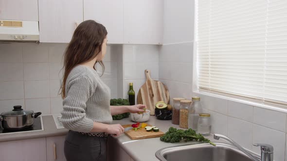 Young female cutting vegetables in the kitchen. Chopping vegetables for salad