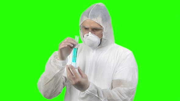 Man in Respiratory and Protective Clothing Holding Test Tube with Blue Liquid alt