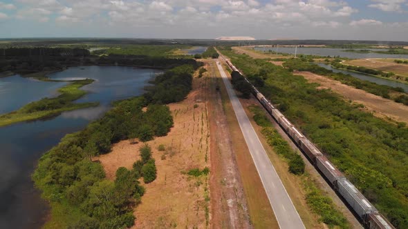 Aerial Of Railroad With A Cargo Train , Country Road And Lakes alt