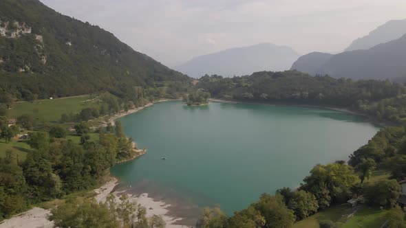 Aerial view: drone shot reveals Tenno lake, Trentino, North Italy. Green landscape during a sunny da alt