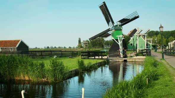 Swans in Canal at Windmills at Zaanse Schans in Holland. Zaandam, Netherlands alt