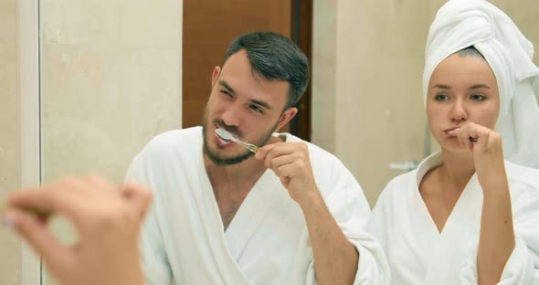 Lovely Couple Brush Teeth Standing Near Mirror in Bathroom