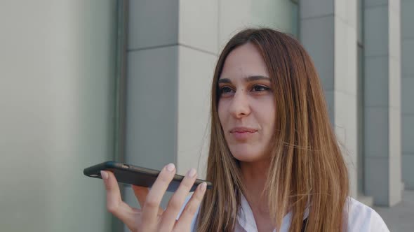 Young Businesswoman Holding Smartphone Speaking Recording Audio Message Talking on Speakerphone alt