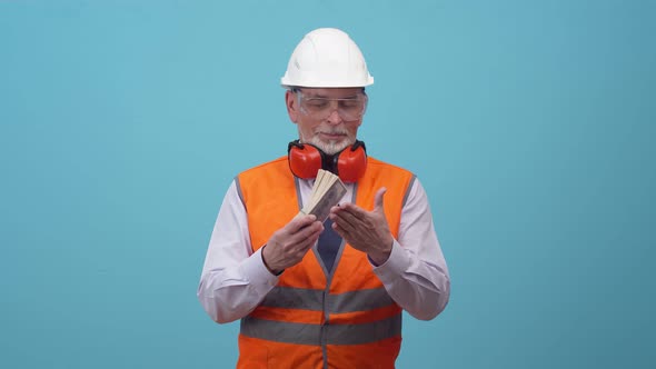 Adult engineer is man in a work vest and helmet slams bundle of dollars on hand alt
