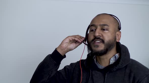 A close up shot of an Indian call centre employee taking a call from a returning customer, the man p alt