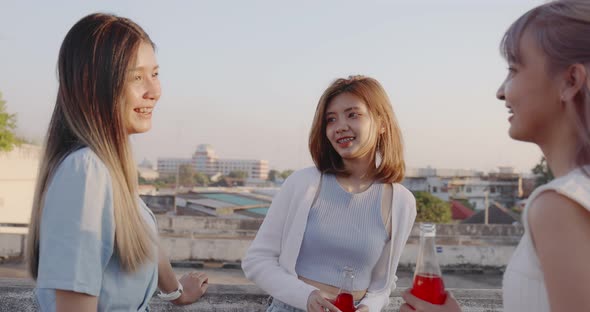 Group of Young pretty Asian girlfriends enjoying with drinking alcohol at rooftop together. alt