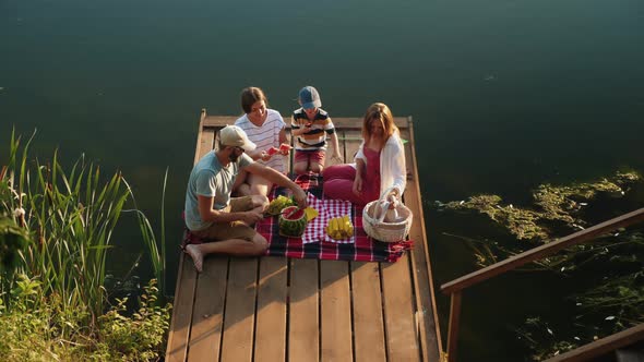 Family Enjoying Picnic on a Wooden Pier alt
