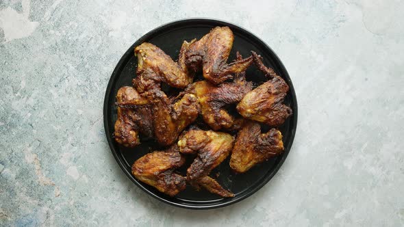 Grilled Chicken Wings on a Black Ceramic Plate. Placed on a Stone alt