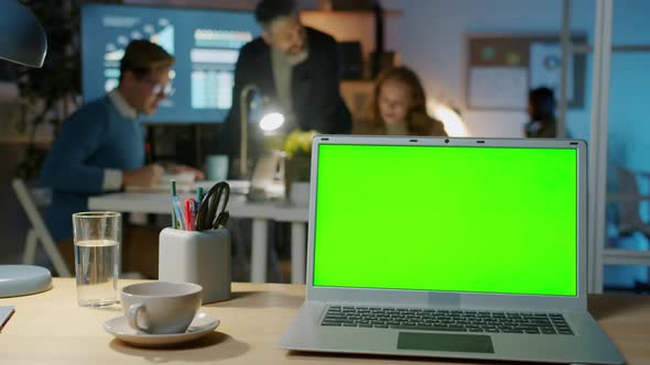 Laptop with Chroma Key Green Screen and Business People Working in Dark Office at Night alt
