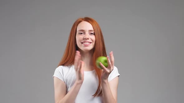 Attractive Redhead Girl with Green Apple. Healthy Fitness and Eating Lifestyle Concept. Slow Motion