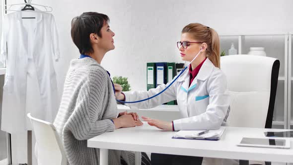 Focused Female Cardiologist Listening Heartbeat of Mature Woman Patient Using Stethoscope alt
