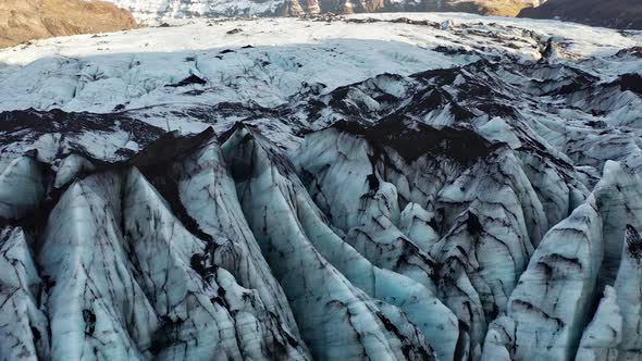 Drone Over Cracked Black And Blue Surface Of Glacier alt