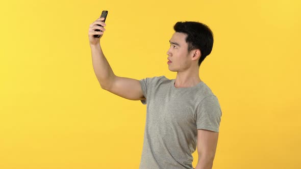 Young Asian man taking selfie on mobile phone