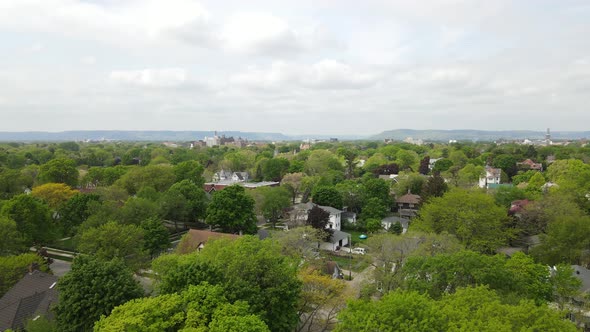 Aerial view of older residential neighborhood with tree lined streets, mountains, and forest.