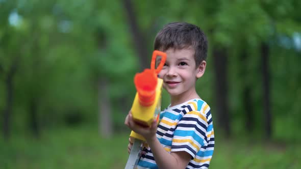 Child Boy Shoots From Toy Weapons Gun Outdoors