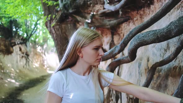 Young Blonde Woman Looking on Exposed Tree Roots in Natural Loess Ravine alt