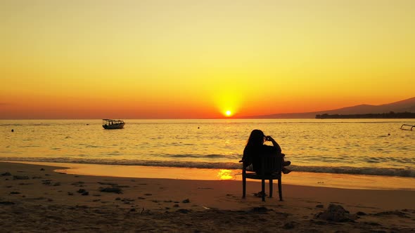 Woman relaxing on the beach during the golden sunset. beautiful calm sea with boats and distant isla alt