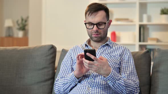 Serious Young Man Using Smartphone at Home  alt