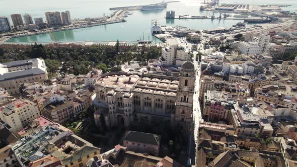 Stunning aerial pan of iconic Malaga Cathedral with port in background; Spain