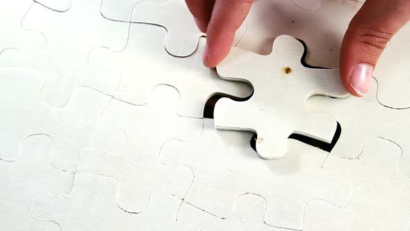 Womans placing missing piece in Jigsaw puzzle alt
