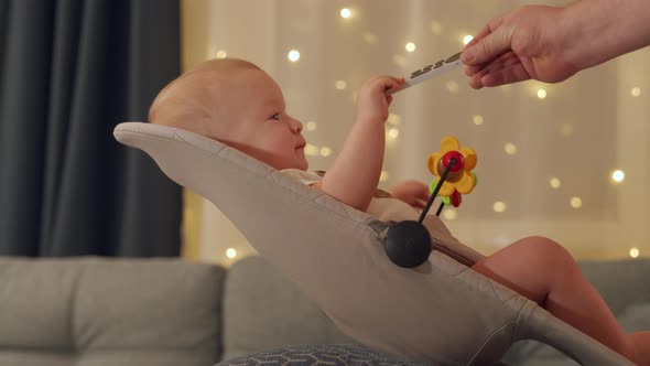 Father Giving Tv Remote to Child to Calm Him Down Happy Kid Sitting in Rocking Chair Watching TV at alt