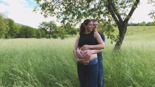 Slow motion shot of pregnant woman and man holding baby belly